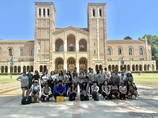 Students shown having fun in front of a University building.